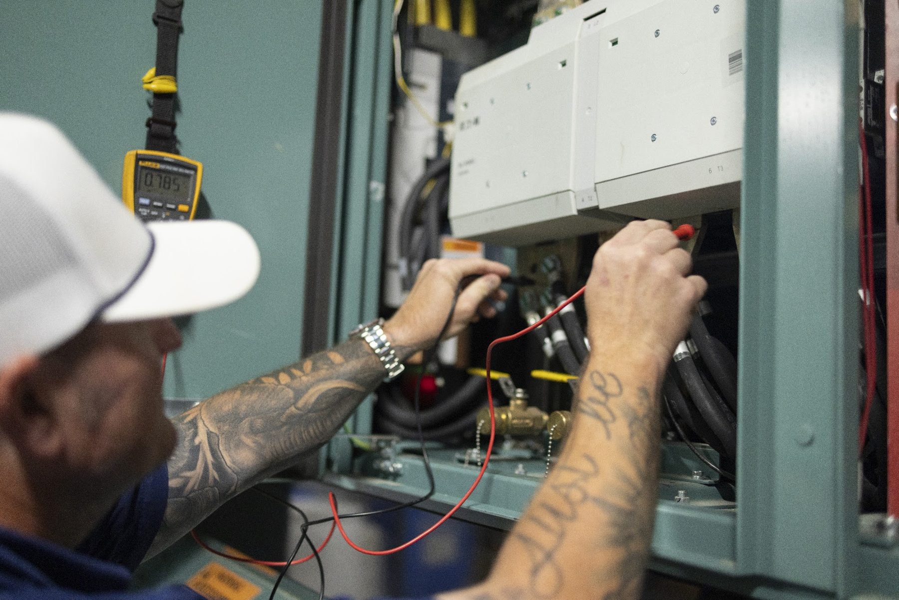 Technician taking electrical readings inside a chiller panel